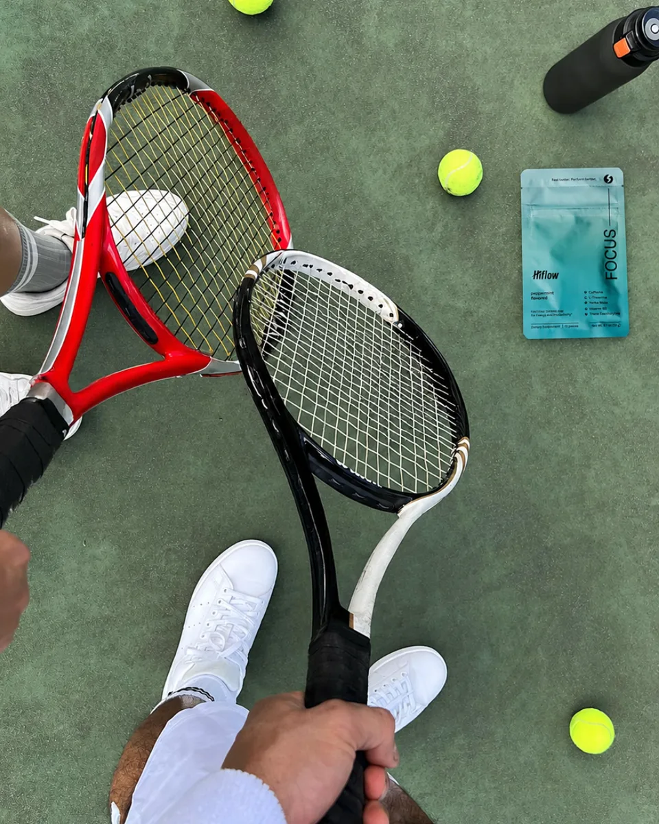 Hiflow Focus peppermint sachet positioned between two tennis rackets and balls on a tennis court